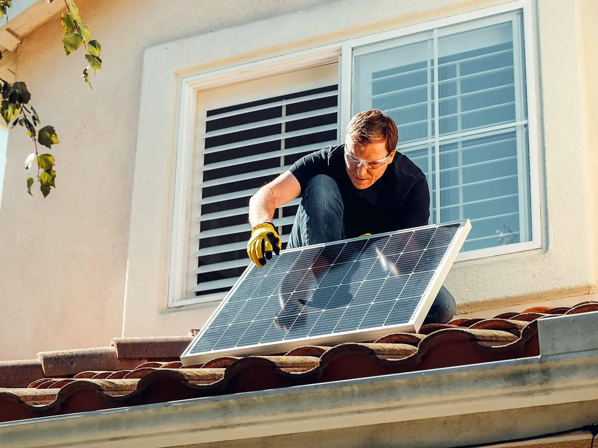 Technician fitting a solar panel onto a tile roof