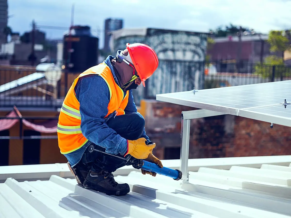 Technician repairing roof-mounted solar panel framing