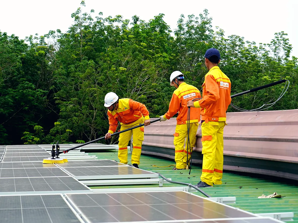 Technicians cleaning rooftop solar panels